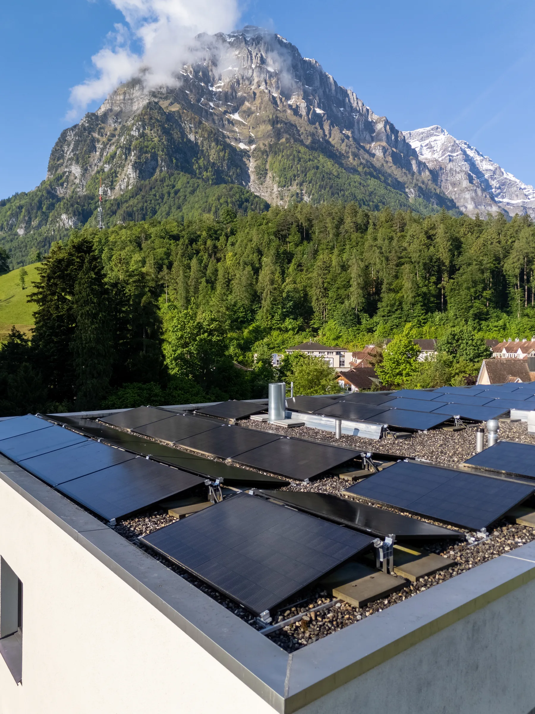 Solarmodule auf einem Flachdach vor Bergkulisse