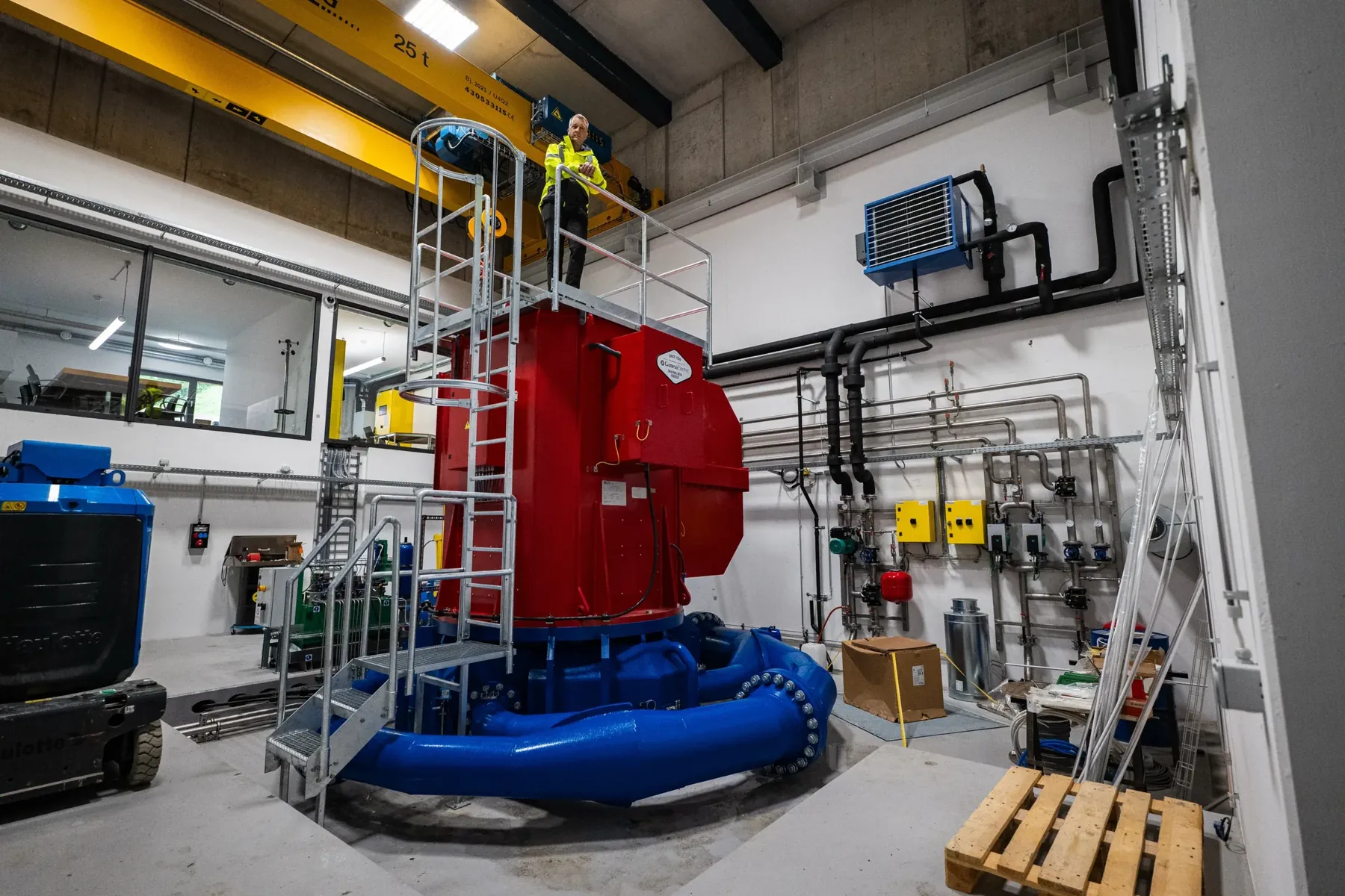 Maschinenhalle eines Kraftwerks mit roter Turbine und blauen Druckleitungen