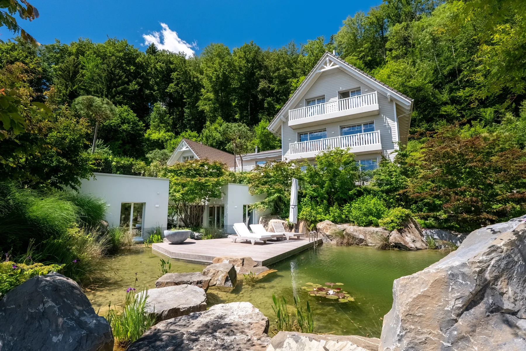 Wohnhaus mit Schwimmteich und Felsen im Garten