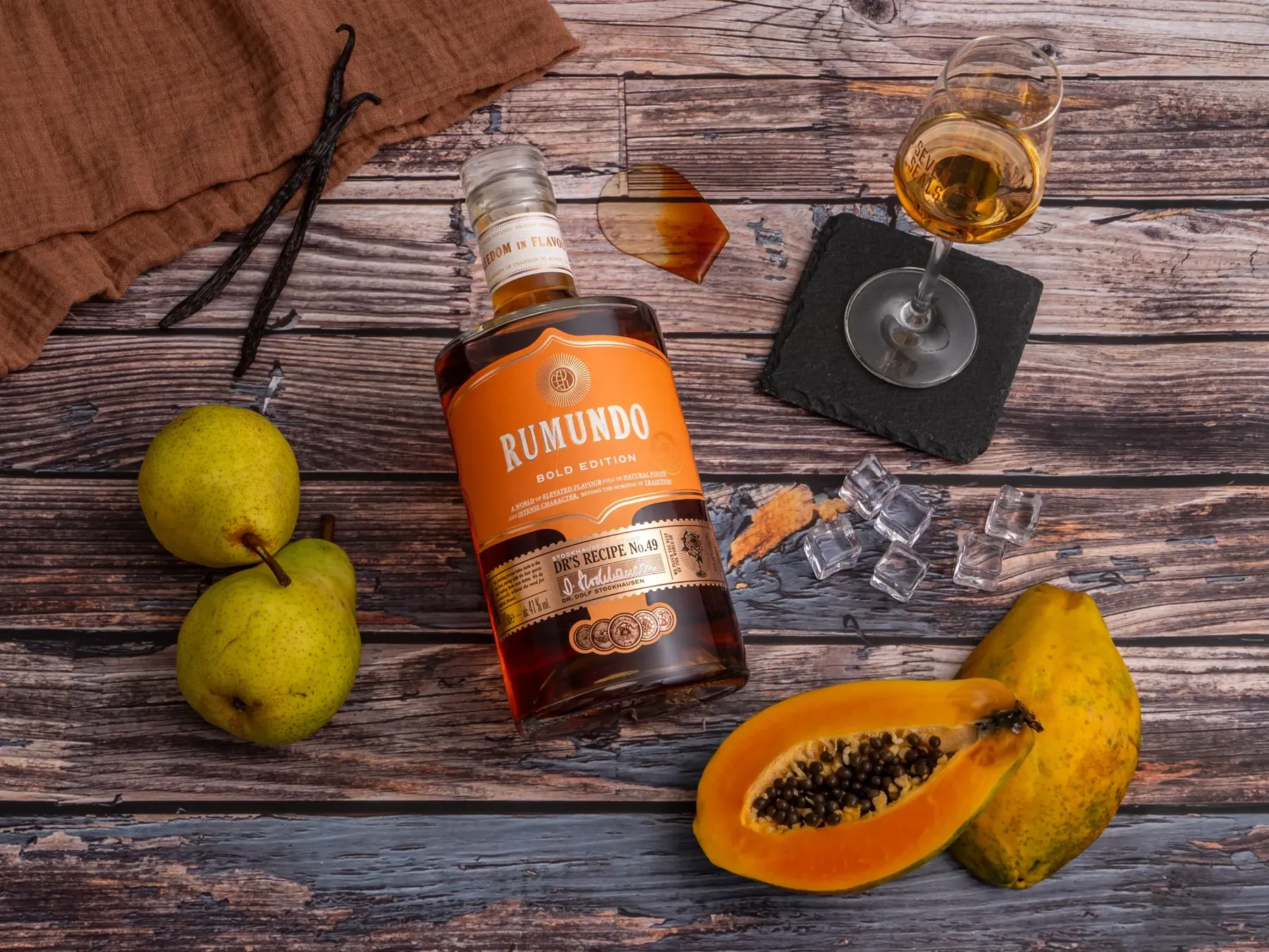 Rumflasche mit Papaya, Birnen und Vanille auf verwittertem Holz