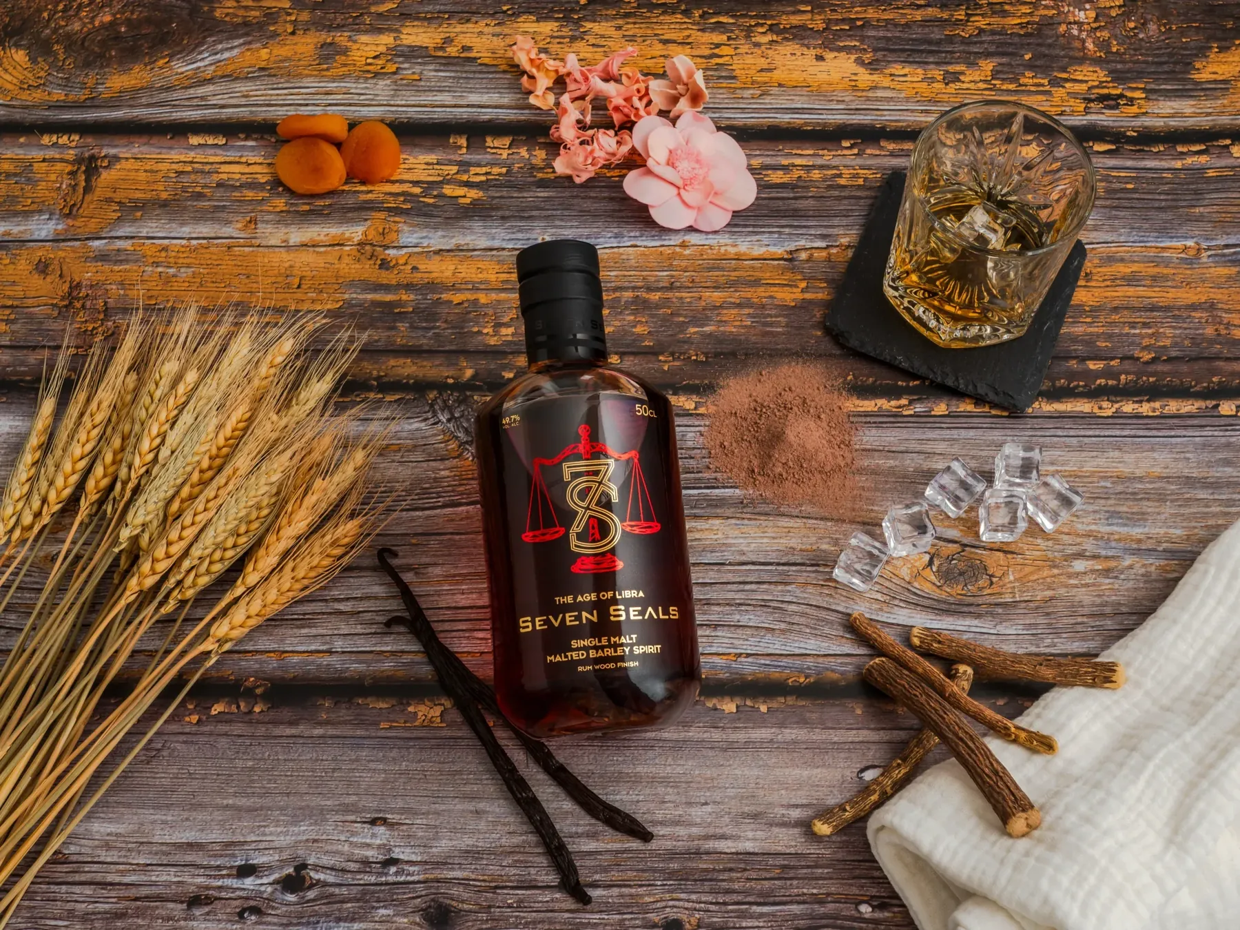 Whiskyflasche von Seven Seals mit Ähren, Vanille und Eis auf Holz